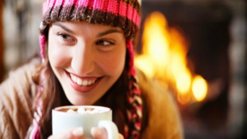 girl-drinking-cocoa-next-to-fireplace